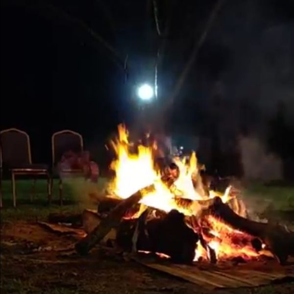 A Person Sitting In A Chair By A Fire At Night
